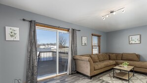 Ein Wohnzimmer mit braunem Sofa, einem Holztisch und Blick durch eine Schiebetür auf eine Terrasse.