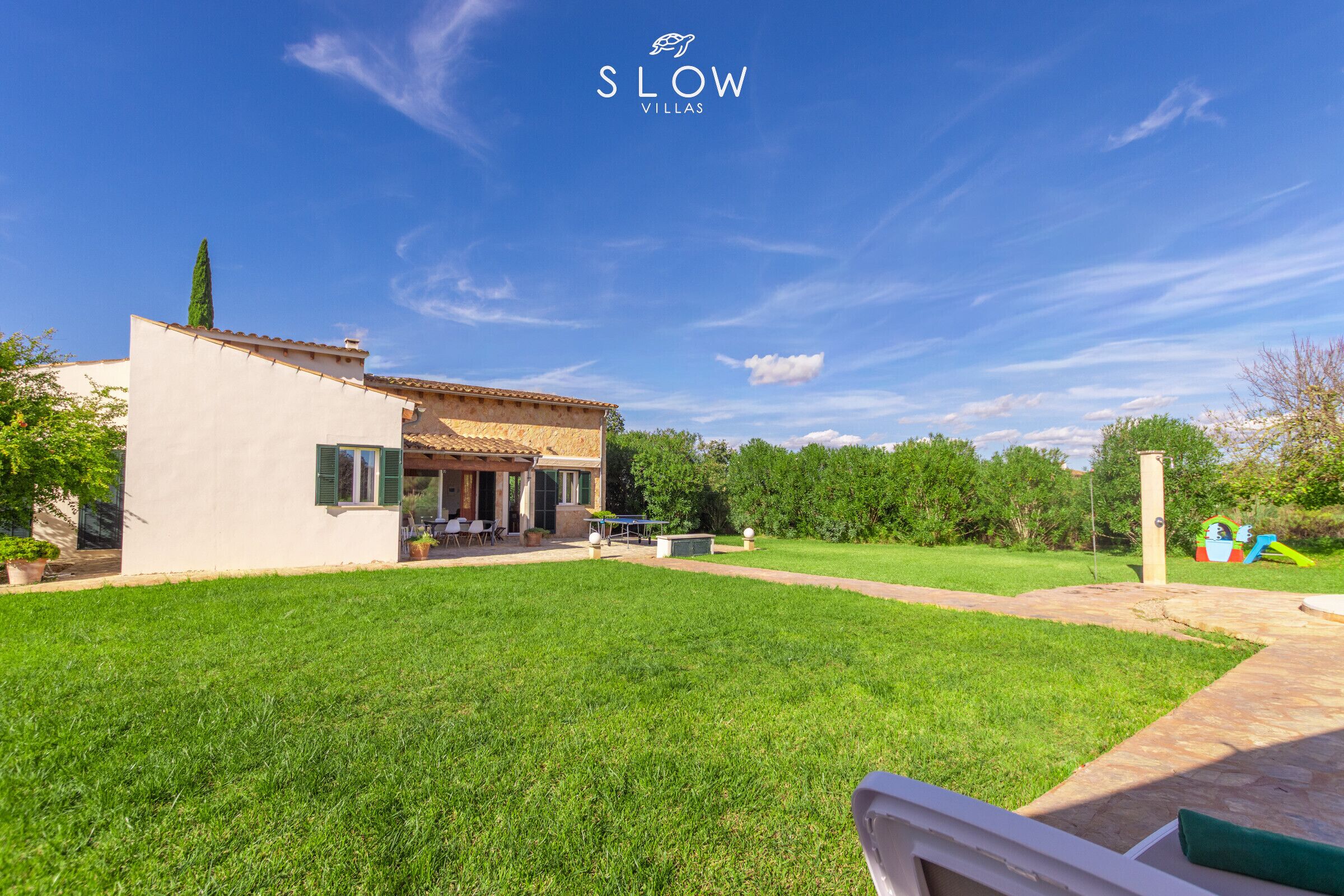A villa with a patio, a lawn, and a play area.