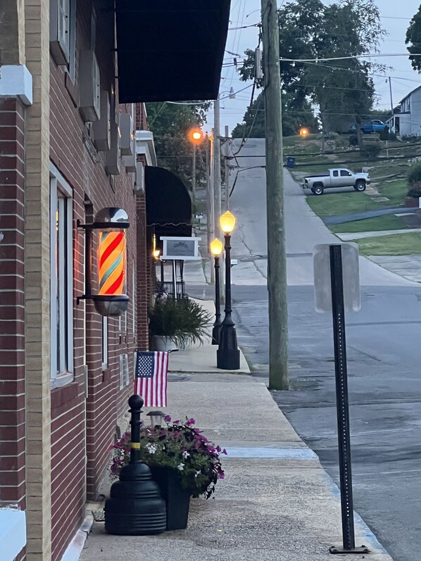 A brick building with a flag, a barber pole sign, and a street lamp. - EC Reed's Mercantile and Hotel (Marble Hill)