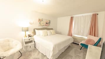 Un dormitorio con cama, mesita de noche, lámpara, silla y ventana con cortinas.
