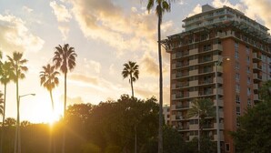 A multi-story hotel with balconies, surrounded by palm trees and a grassy area. - Your Bay View Escape in Coconut Grove, Pool & Gym (Miami)
