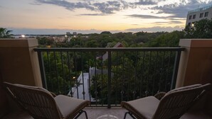 A balcony with two wicker chairs and a small table, overlooking a cityscape with buildings and trees. - Your Bay View Escape in Coconut Grove, Pool & Gym (Miami)