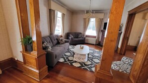 A spacious living room with a grey sofa, a white coffee table, and a patterned rug.