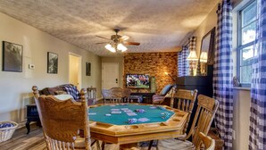 A room with a poker table, chairs, a television, and a ceiling fan. - The Woodland Cottage Smoky Mountain Hideaway (Sevierville)