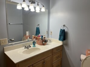 Un baño con un espejo grande, dos lavamanos, armarios de madera y un perchero para toallas.