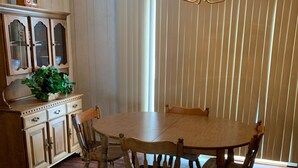 Un coin repas avec une table et des chaises en bois, un lustre et un meuble avec des tiroirs.