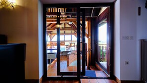 Une porte ouverte donnant sur un patio aménagé avec du mobilier d’extérieur et un mur en briques.