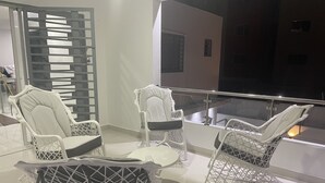 A balcony with white wicker furniture, including chairs and a table, and a glass railing. - 5 minutes from la caleta beach 10 minutes from casa de campo la romana (romana del este)
