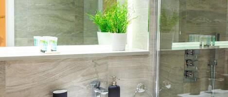 Une salle de bain moderne avec un lavabo blanc, un robinet chromé et une plante en pot posée sur le rebord de la fenêtre.