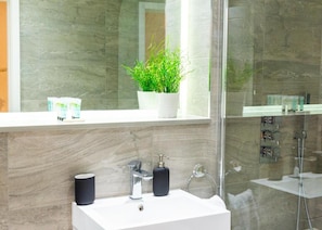 A modern bathroom with a white sink, chrome faucet, and a potted plant on the window sill. - St Albans- High Street-business-leisure (St Albans)