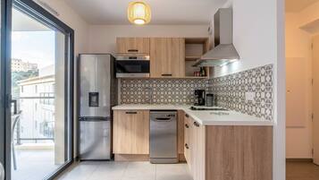 Een moderne keuken met een inbouwkoelkast, oven en vaatwasser. Houten kasten, een betegelde spatwand en een hanglamp sieren de ruimte.