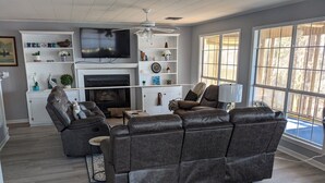 A living room with a fireplace, leather sofa, television, and large windows. - Toledo Bend on Lanana Bay Waterfront Camp Boathouse Dock Subdivision Boat Launch (Many)