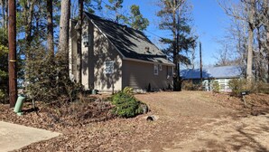 A single-story house with a sloped roof, surrounded by trees and a gravel driveway. - Toledo Bend on Lanana Bay Waterfront Camp Boathouse Dock Subdivision Boat Launch (Many)