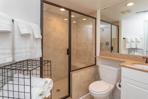 Ein modernes Badezimmer mit einer Duschkabine, einer weißen Toilette und einem Waschbecken mit Granitplatte.