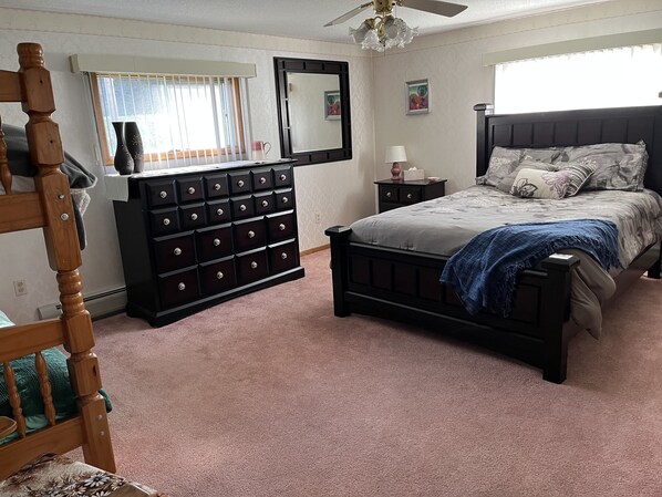 Quarto com cama, cômoda, mesa de cabeceira e uma cadeira.