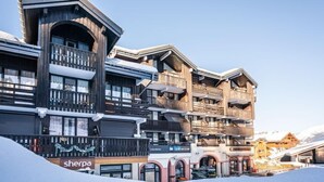 Un hôtel à plusieurs étages, doté de balcons, avec une station de ski en toile de fond.
