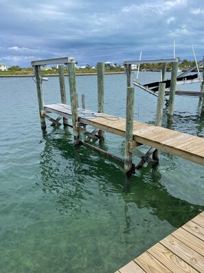 A wooden dock extending into a body of water with clear water and a cloudy sky in the background.