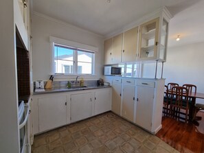 Kitchen with sink, microwave, and toaster, adjacent to a dining area with a table and chairs.