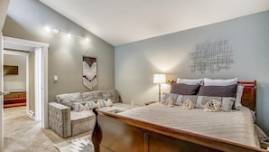 A bedroom with a bed, a nightstand, a lamp, a chair, and a wall hanging. - Quick Walk to lift and town (Breckenridge)