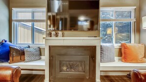 A living room with a fireplace, a sofa, and a window with blinds. - Quick Walk to lift and town (Breckenridge)
