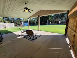 A covered patio with a ceiling fan, a table, and two chairs.