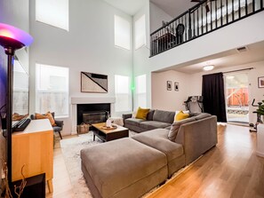 A spacious living room with a fireplace, a sofa set, a coffee table, and a TV. - Friends, Family & Dog Stay in Monterey Peninsula with AC & Grill (Salinas)