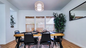 A dining area with a wooden table, black chairs, a patterned rug, and a hanging light fixture. - Friends, Family & Dog Stay in Monterey Peninsula with AC & Grill (Salinas)