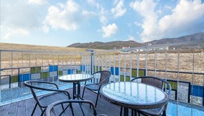 Relax on the furnished terrace with a clear view of the surrounding landscape, featuring a distant mountain range and a body of water.