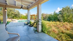 A covered patio with outdoor seating, a pool, and a view of the surrounding garden. - Villa Aphrodite:Pet-friendly, 3 bedrooms,pool, WiFi, mobility-friendly (Poulades)