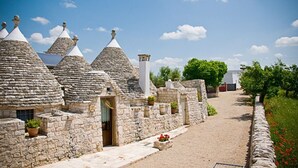 Une rangée de maisons en pierre aux toits coniques, un chemin de gravier et un ciel bleu azur.