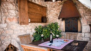 A rustic stone building with a wooden table set for two, a bottle of wine, and a plate of food. - Dell'Aia: 1800s trullo house with garden view and ancient farmyard (Martina Franca)