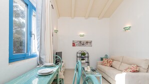 Un coin repas avec une table et des chaises bleues, un canapé et une petite table sur laquelle est posée une plante.