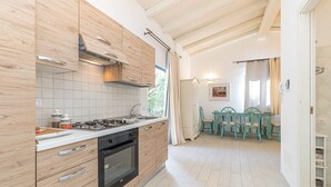 Une cuisine moderne avec des meubles en bois, une cuisinière à gaz et un coin repas comprenant une table et des chaises.