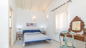 Une chambre à coucher comprenant un lit, des tables de chevet, une chaise, une commode et un miroir.