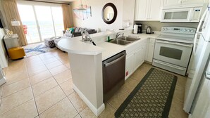 A modern kitchen with a central island, white cabinetry, a microwave, stove, and a sink.