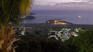 A coastal view with a lit-up resort area, a runway, and a body of water. - Beautiful Apartment w- gorgeous expansive views, beautiful fruit trees & gardens (ST. THOMAS)