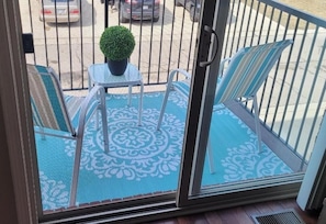 Enjoy the view from this balcony with a table, chairs, and a potted plant.
