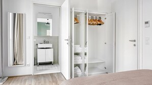 A modern bedroom with a large bed, a wardrobe with hanging space, and a bathroom with a sink and mirror. - Modern Leopoldstadt 1BR w/ Rooftop & BBQ, near Metro U2, by Blueground (Vienna)