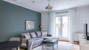 A modern living room with a grey sofa, a glass coffee table, and a dining table with chairs. - Newly renovated Innere Stadt 1BR w/Elevator, near Metro U3, by Blueground (Vienna)