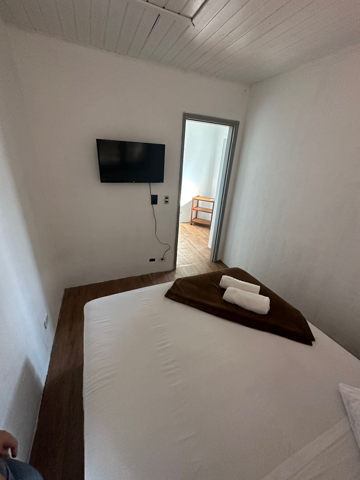 A hotel room with a bed, a TV mounted on the wall, and a door leading to a balcony.