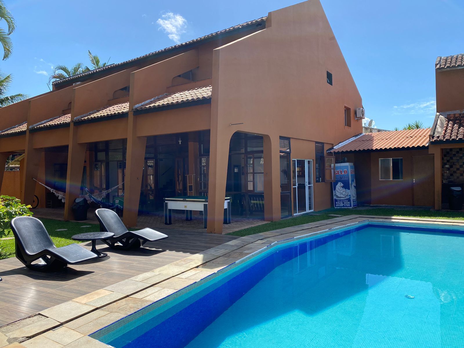 Una casa moderna con piscina, mobiliario de exterior y un patio visible.