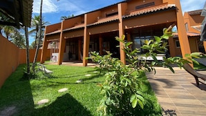 A two-story building with a tiled roof and a covered patio area. - Ponta dos Corais (Guarujá)