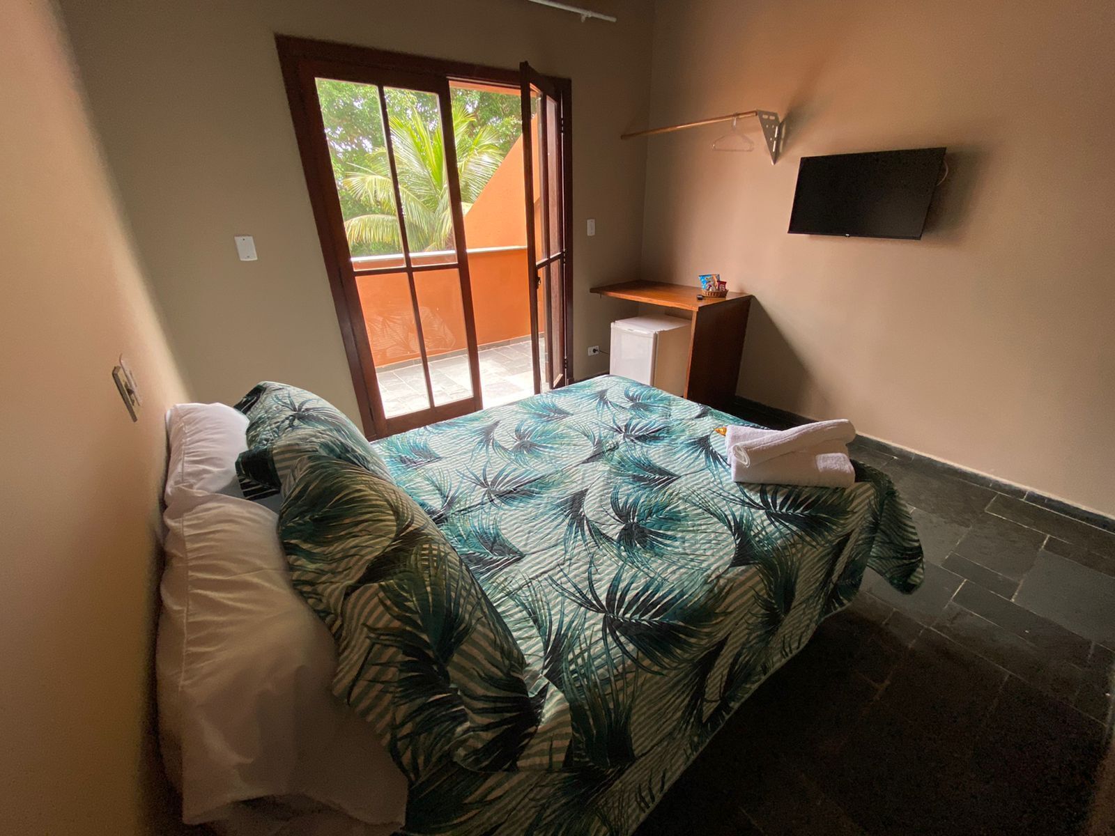 Una camera da letto con un letto, una scrivania e un televisore appeso al muro.