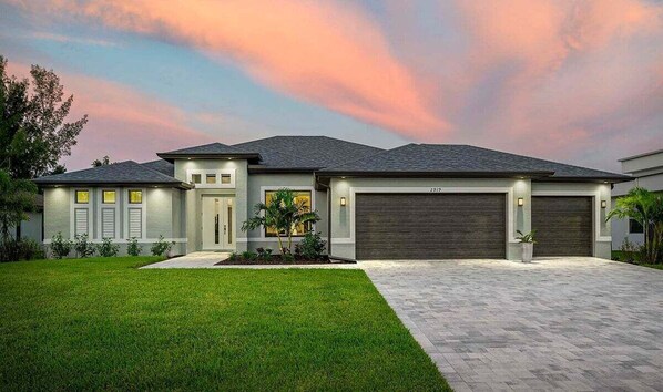 A modern two-story house with a well-maintained lawn, a driveway, and a garage. - Villa Tahiti - Beautiful Brand New Home (Cape Coral)