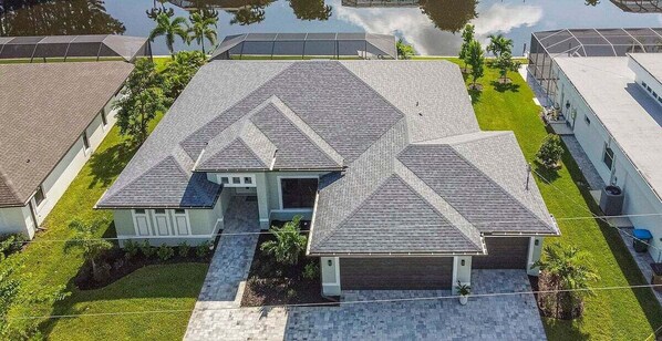 A residential property with a symmetrical roof design, a central entrance, and a well-maintained lawn.