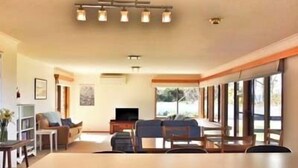 A spacious living room with a large dining table, comfortable seating, and a television. - Sea Eagle, Dover's beautiful Roaring Beach (Surveyors Bay)