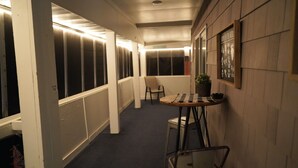 Ein schmales Gang mit einem kleinen Tisch, Stühlen, einem Blumentopf und einem gerahmten Bild an der Wand.