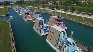 Eine Reihe von schwimmenden Häusern liegen in einem Kanal vor Anker, jedes mit einem einzigartigen Design und mehreren Ebenen.