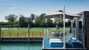 Un bateau doté d’un espace salon couvert, d’une piscine et offrant une vue sur une zone verdoyante et l’eau.