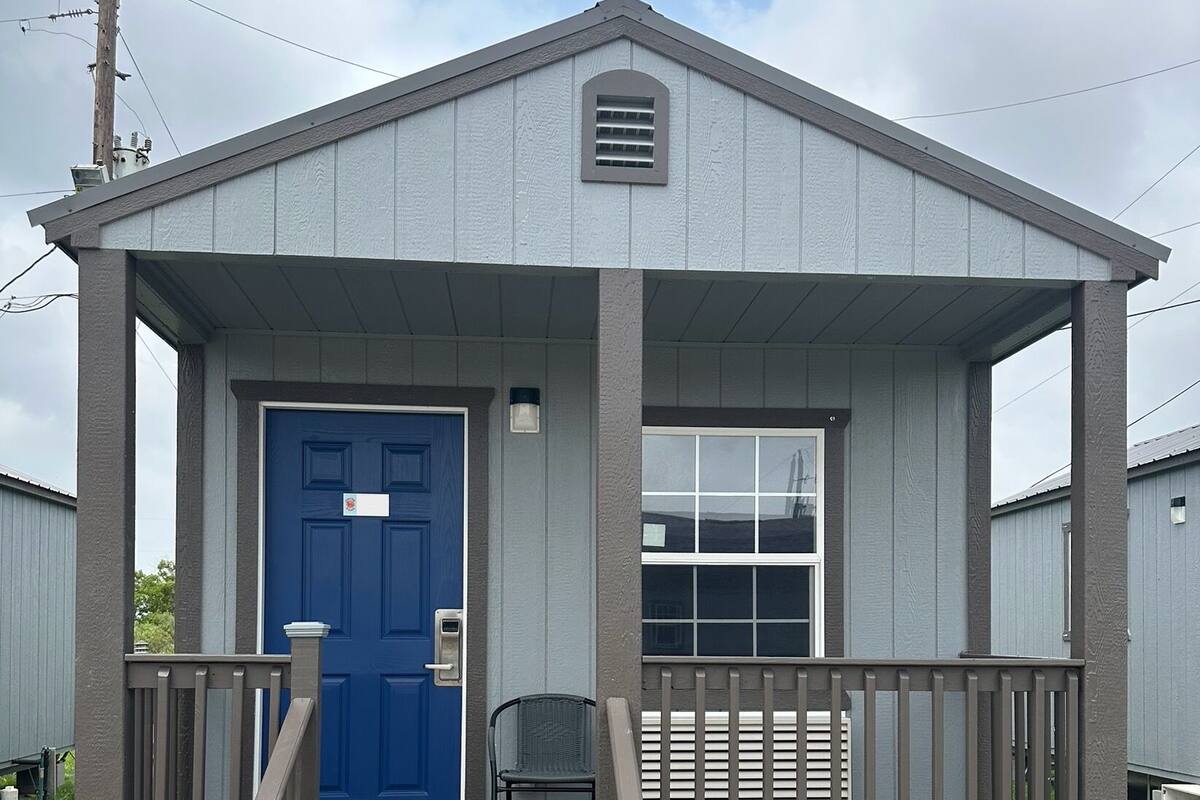 A small, single-story building with a blue door and a window.